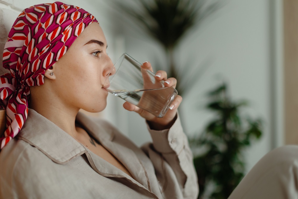 Jonge vrouw met hoofddoek drinkt glas water