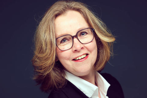 blonde vrouw met bril tegen donkerblauwe achtergrond