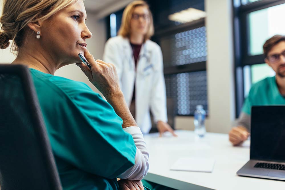 groep vrouwelijke zorgprofessionals in overleg aan een tafel