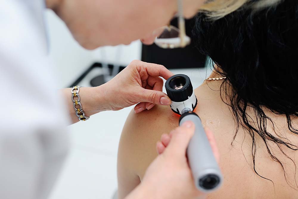 dermatoloog onderzoekt huid op schouder van persoon met lang haar