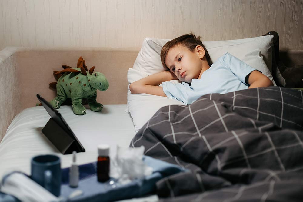 jongetje ziek in bed met knuffel