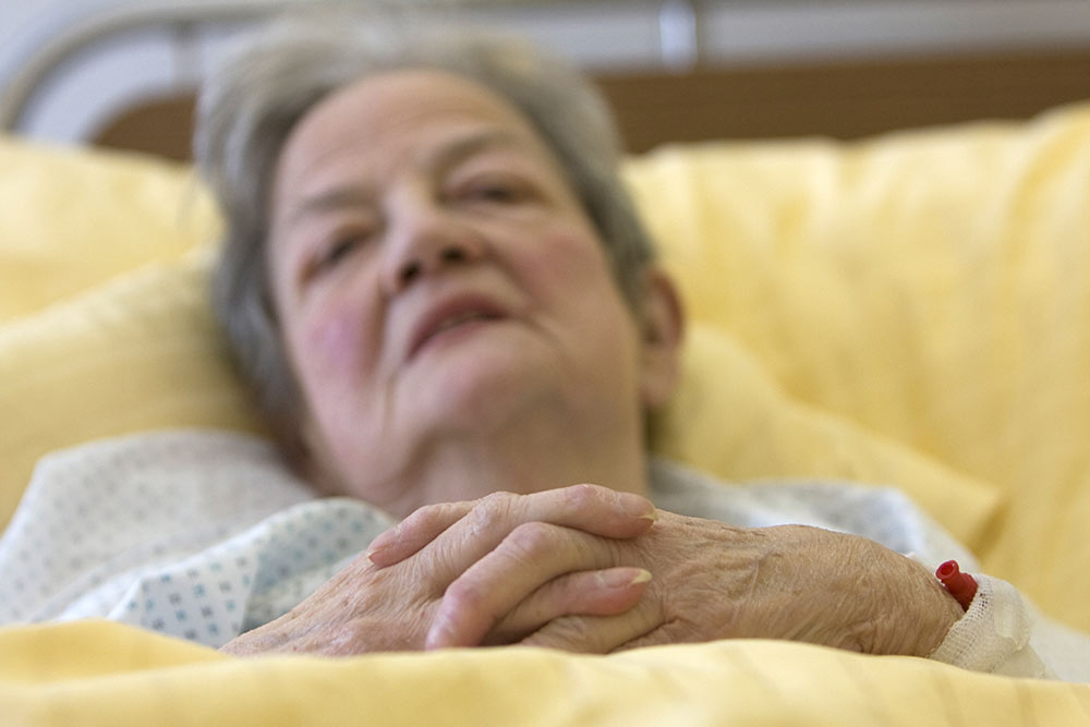 zieke oudere vrouw in bed met gele lakens, slapend