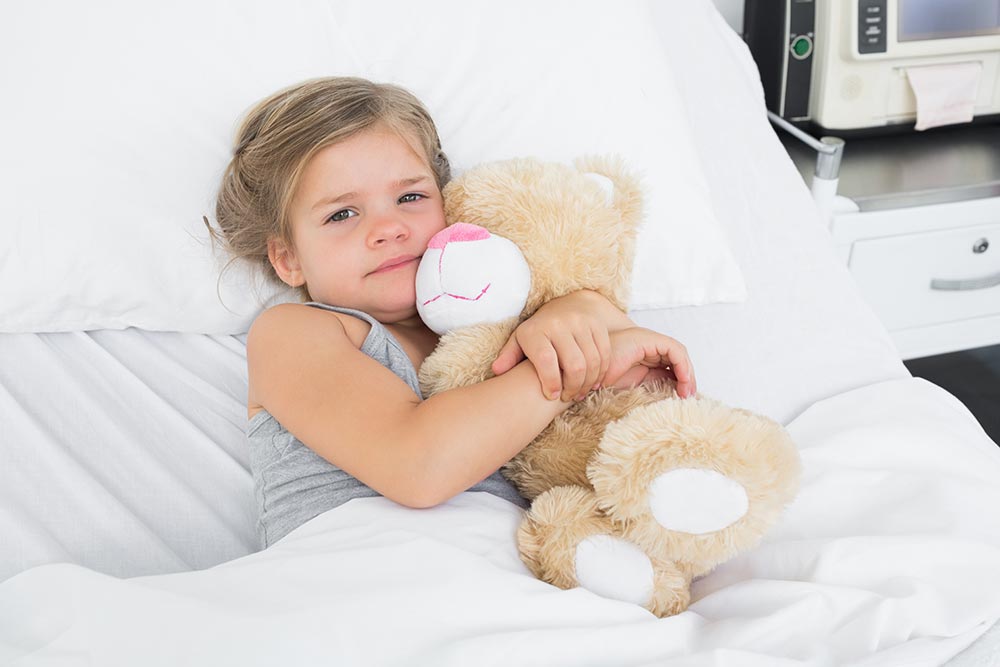 meisje in ziekenhuisbed met teddybeer