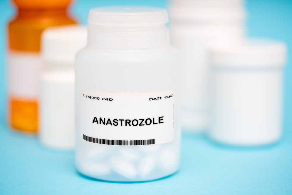 een wit pillenpotje met het label anastrozol met daarachter vervaagd nog meer pillenpotjes tegen een lichtblauwe achter- en ondergrond