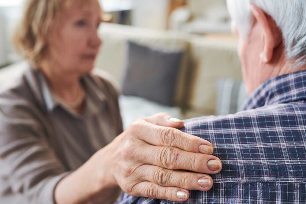 Hand van mantelzorger op schouder van man