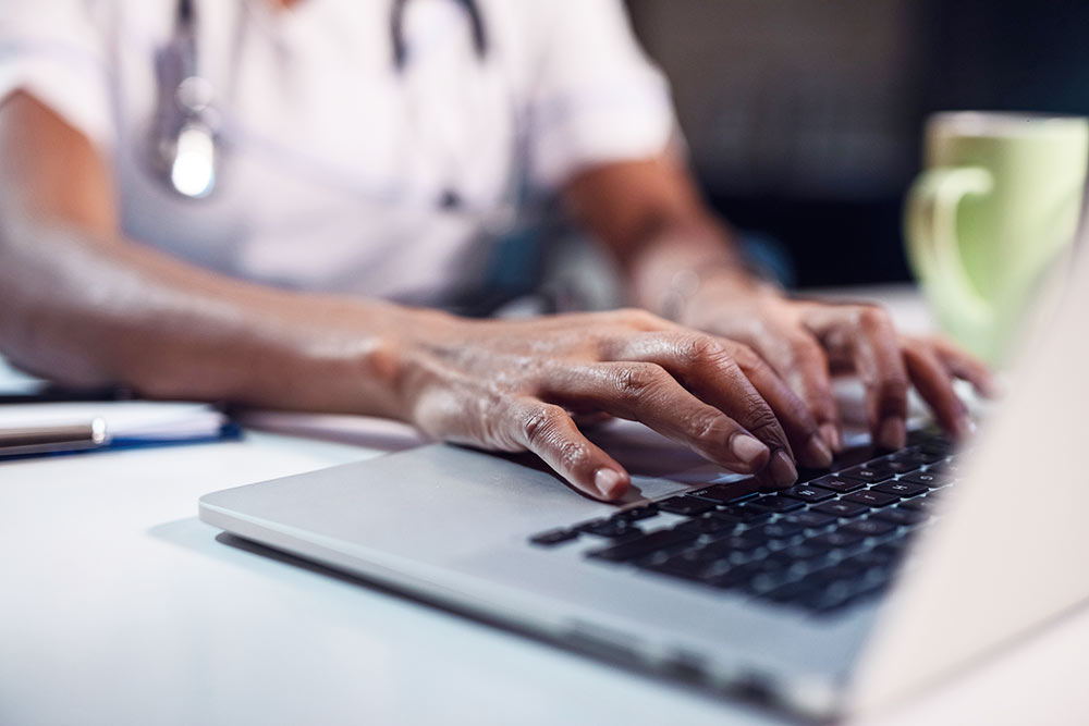 Vrouwelijke zorgprofessional typt achter laptop